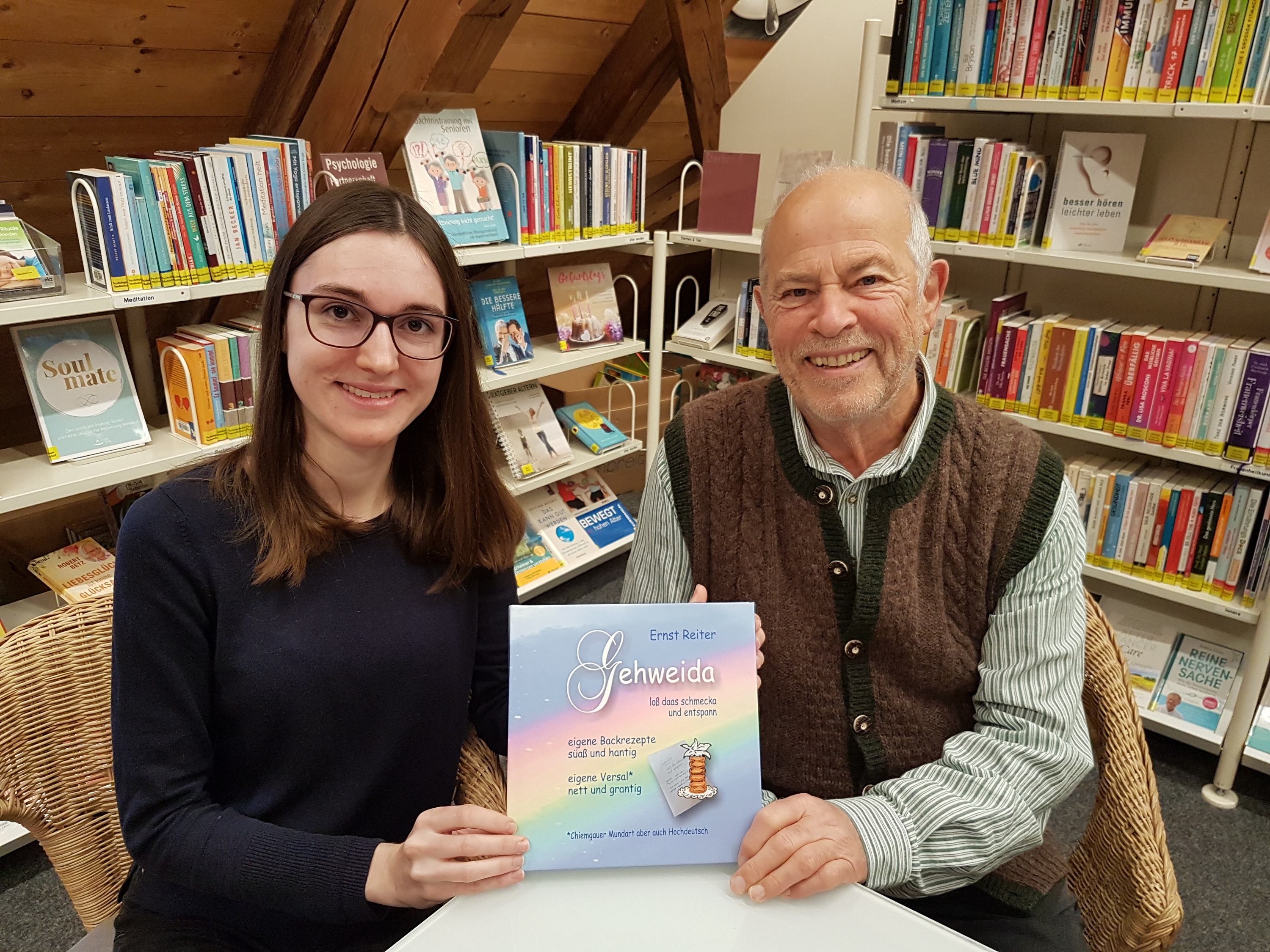 (v.l.n.r.) Büchereileiterin Melanie Schieber freut sich, mit dem Priener Verserlschreiber und Konditormeisters i. R. Ernst Reiter einen neuen Buchpaten gewonnen zu haben, der den Leserinnen und Lesern der Bücherei Prien viel Freude mit seiner Lektüre und gutes Gelingen beim Nachbacken des einen oder anderen Rezeptes wünscht. Bildrechte Prien Marketing GmbH 