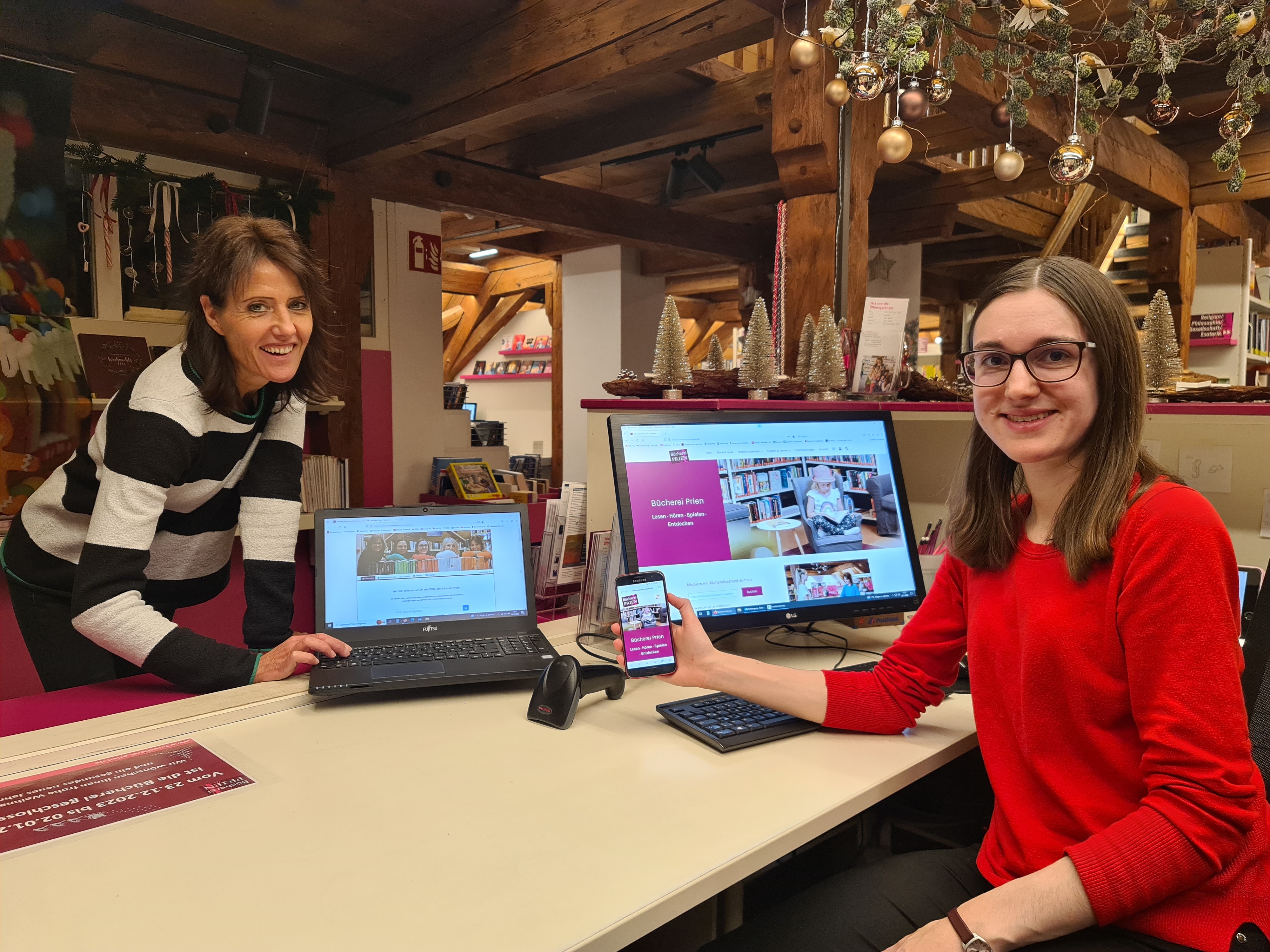 (v.l.n.r.) Büchereimitarbeiterin Bianca Radlinger und die Büchereileitung Melanie Schieber stellen die neue Webpräsenz der Bücherei Prien vor.Foto: Prien Marketing GmbH