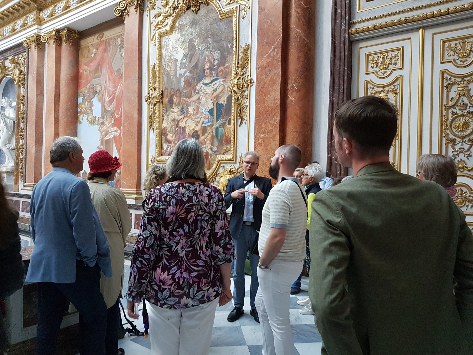 Das Foto zeigt den Historiker Marcus Spangenberg und die Teilnehmenden der Veranstaltung im August 2023 im Prunktreppenhaus von Schloss Herrenchiemsee. Foto: Prien Marketing GmbH