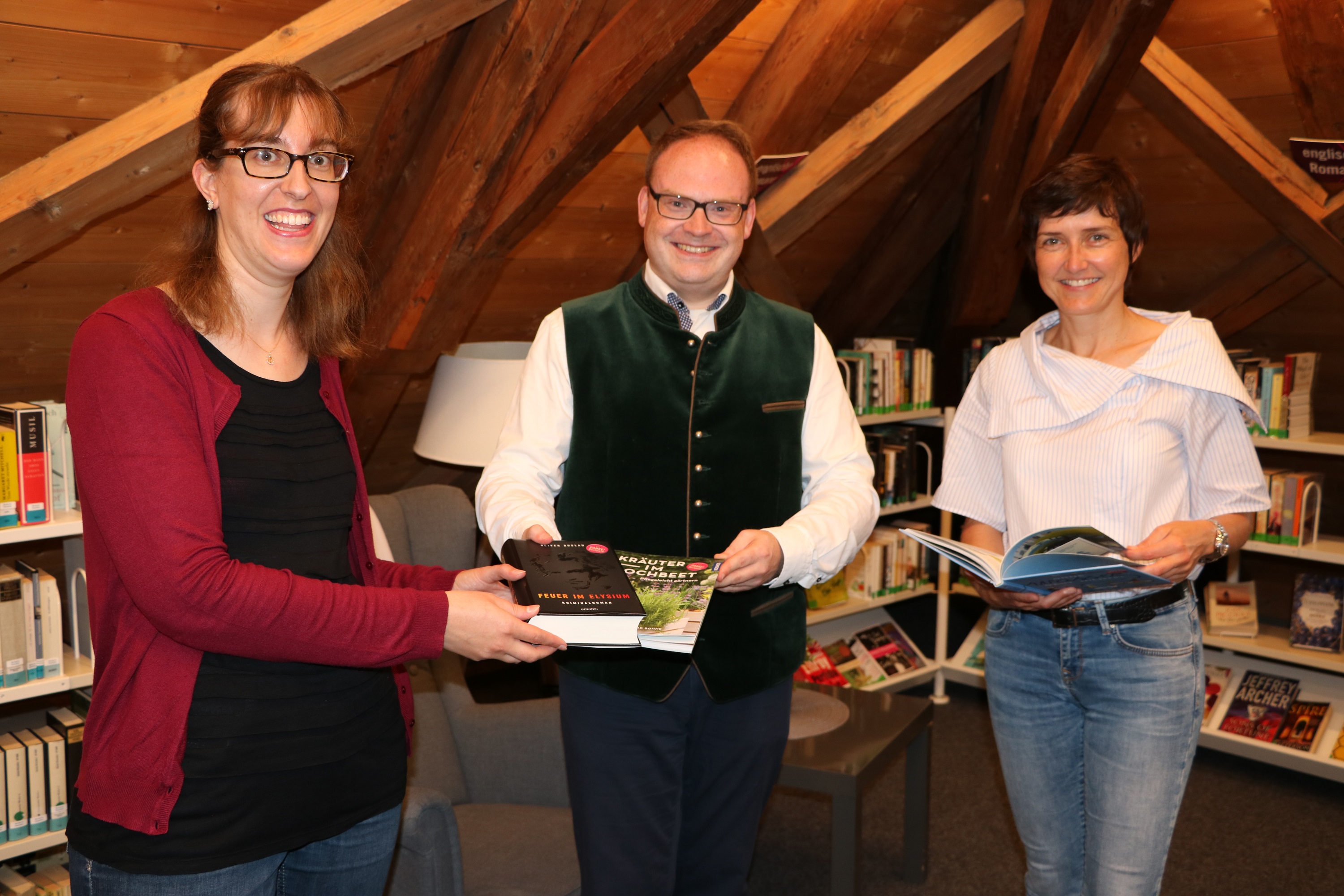 Büchereileiterin Christina Klasna (links im Bild) und die Geschäftsführerin der Prien Marketing GmbH Andrea Hübner (rechts im Bild) nehmen die ersten drei Bücher in Empfang, deren Patenschaft der Erste Bürgermeister der Marktgemeinde, Andreas Friedrich, übernommen hat. Bildrechte: Prien Marketing GmbH