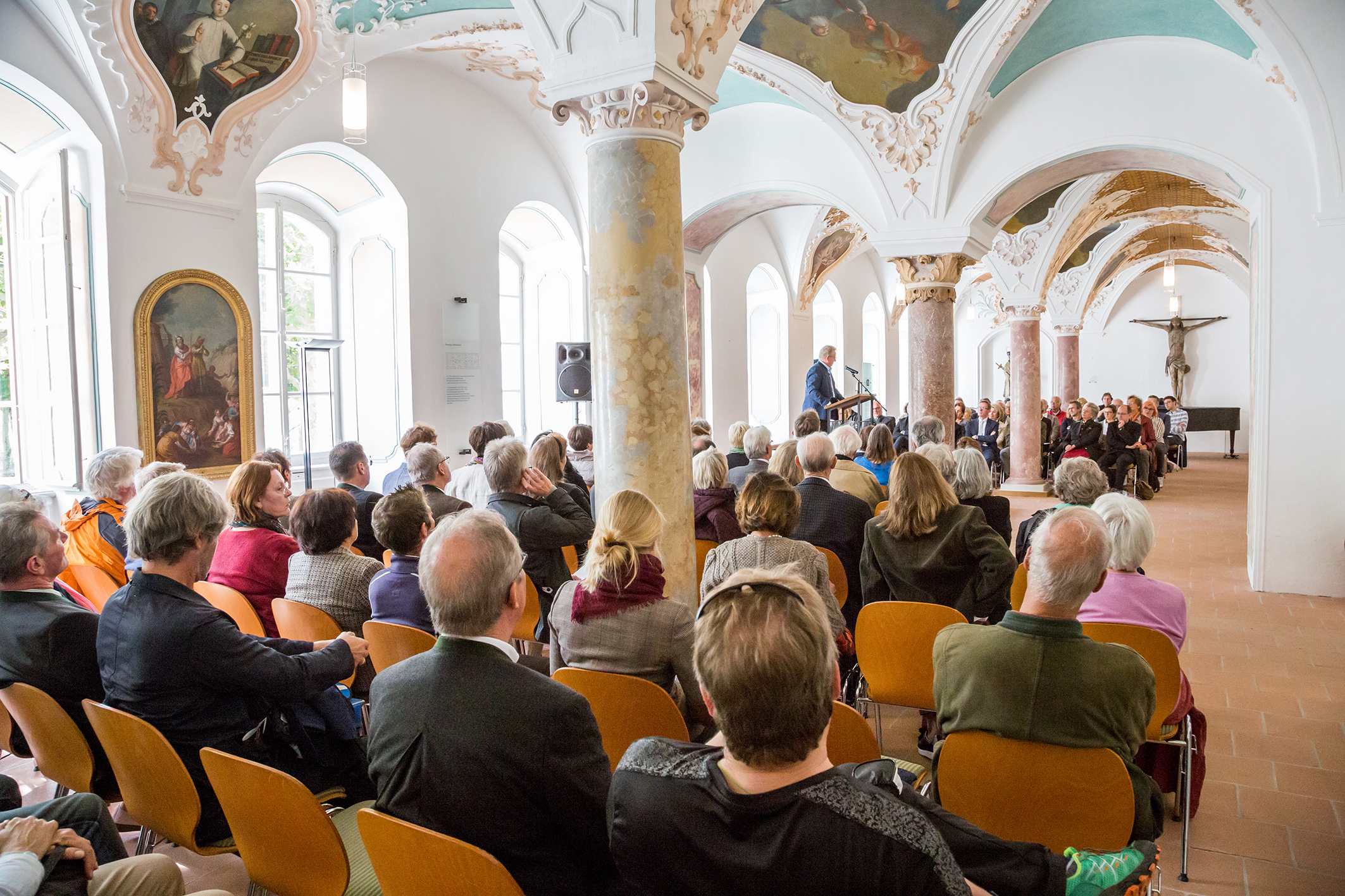 Audio-Guides als Jubiläumsgeschenk an die Schlösserverwaltung - Dr. Friedrich von Daumiller, 1. Vorsitzender der Vereinigung der Freunde von Herrnchiemsee bedankt sich für die gute Zusammenarbeit bei Oberstudienrat Andreas Hauptmann und den beiden Abiturientinnen des LTGs, Vera Mair und Julia Hännes. Referat von Dr. Harald Parigger, Direktor der Zentrale für politische Bildungsarbeit, zum Thema „Götter, Völker, Grundgesetz. Einige Gedanken zu einer modernen Werte- und Demokratieerziehung“ im voll besetzten Bibliothekssaal.(Bildrechte:Prien Marketing GmbH)