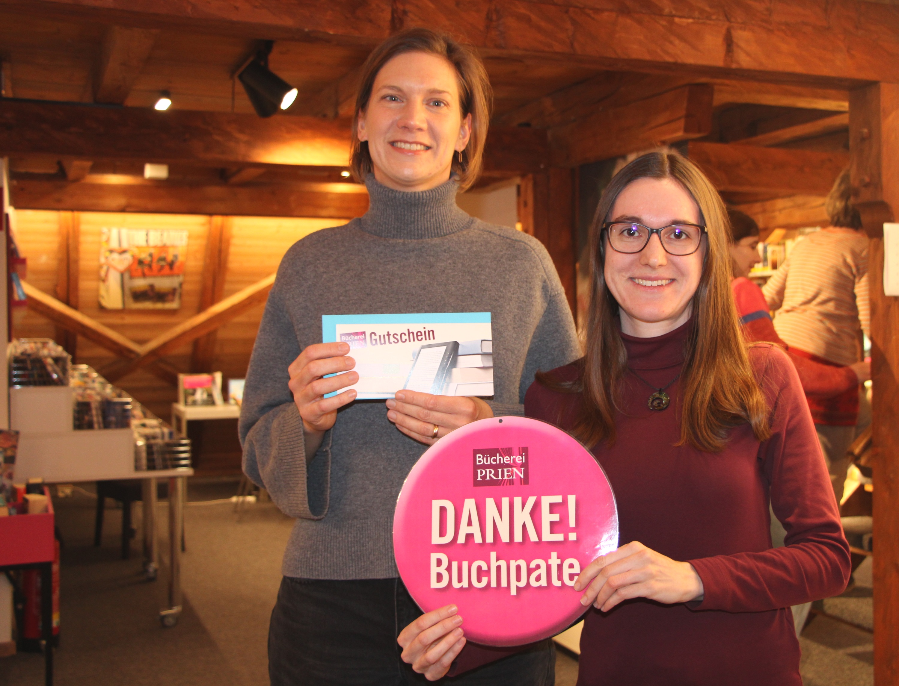 (v.l.n.r.) Büchereileiterin Melanie Schieber gratuliert der Gewinnerin der Verlosung „Danke Buchpate“. Manja Klingelhöffer freut sich über eine Jahresgebühr für die Bücherei Prien. Zweimal im Monat besucht die Leserin die Einrichtung im Dachgeschoss des Haus des Gastes und leiht überwiegend Romane sowie Kinderbücher aus.Bildrechte: Markt Prien a. Chiemsee (v.l.n.r.) Büchereileiterin Melanie Schieber gratuliert der Gewinnerin der Verlosung „Danke Buchpate“. Manja Klingelhöffer freut sich über eine Jahresgebühr für die Bücherei Prien. Zweimal im Monat besucht die Leserin die Einrichtung im Dachgeschoss des Haus des Gastes und leiht überwiegend Romane sowie Kinderbücher aus.Bildrechte: Markt Prien a. Chiemsee