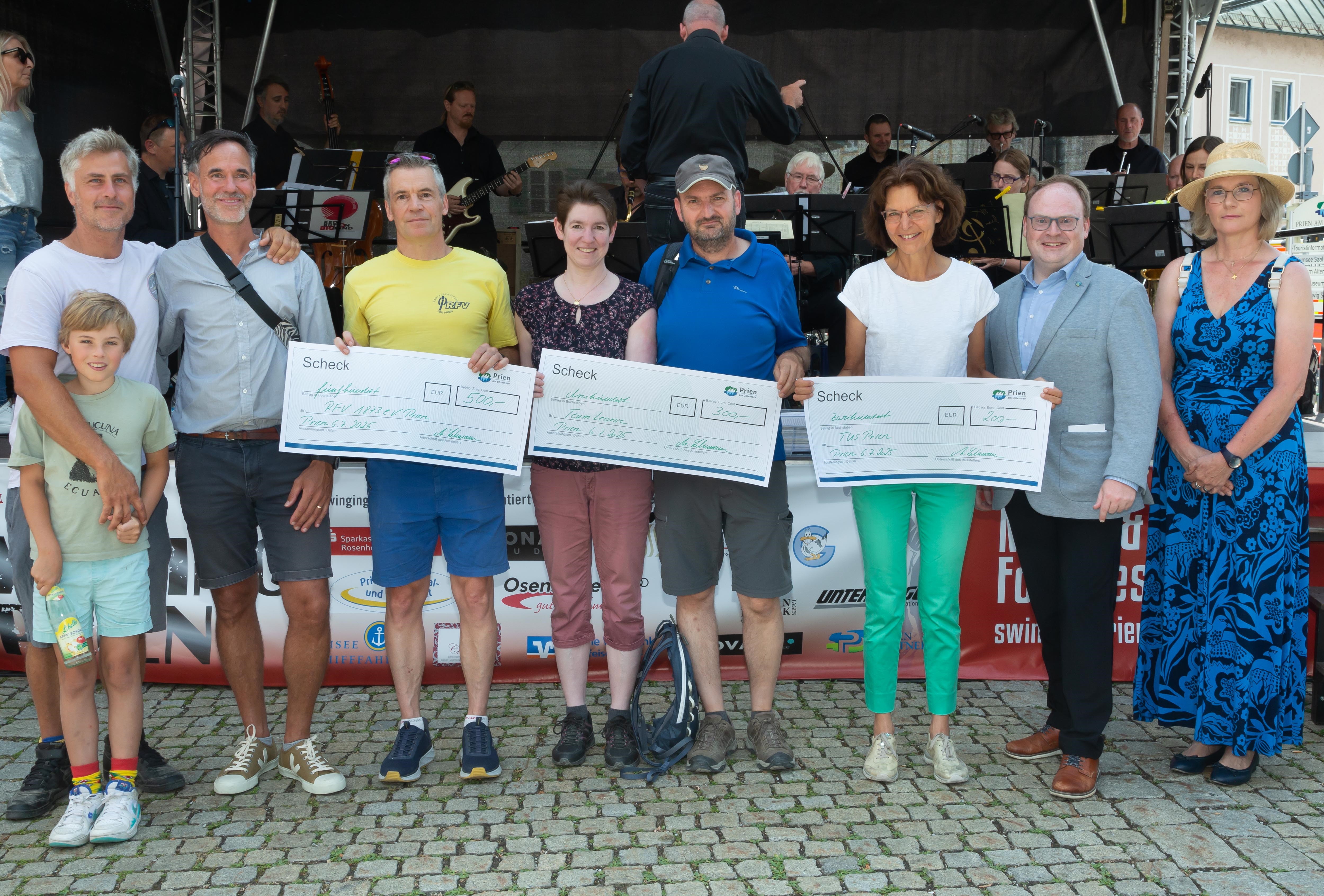 Prämierung Stadtradeln 2025: (v.l.n.r.) Die beiden Fahrradbeauftragten der Marktgemeinde Prien, Maximilian Kölbl und August Pflugfelder gratulieren den Stellvertretern der erfolgreichsten Priener Radel-Teams. Der Erste Vorstand des RFVs 1893 Prien e.V. Winfried Kober, Martina Sänger-Seiffer und Marcus Seiffer vom „Team Leonie“ sowie die Teilnehmerin vom TuS Verein Prien Josefine Hobmaier nehmen ihre symbolischen Schecks von dem Ersten Bürgermeister Andreas Friedrich und der Mitarbeiterin der Marktgemeinde Prien Martina Lehmann entgegen. Bildrechte: Anita Berger Prämierung Stadtradeln 2025: (v.l.n.r.) Die beiden Fahrradbeauftragten der Marktgemeinde Prien, Maximilian Kölbl und August Pflugfelder gratulieren den Stellvertretern der erfolgreichsten Priener Radel-Teams. Der Erste Vorstand des RFVs 1893 Prien e.V. Winfried Kober, Martina Sänger-Seiffer und Marcus Seiffer vom „Team Leonie“ sowie die Teilnehmerin vom TuS Verein Prien Josefine Hobmaier nehmen ihre symbolischen Schecks von dem Ersten Bürgermeister Andreas Friedrich und der Mitarbeiterin der Marktgemeinde Prien Martina Lehmann entgegen. Bildrechte: Anita Berger